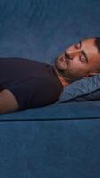 Resting man. Media. A large comfortable blue sofa and a man resting on it who sleeps after a hard day's work. video