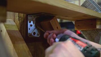 Carpenter working at workshop. Media. Worker using a screwdriver for assembling wooden construction. video