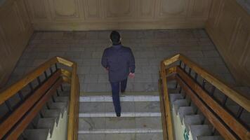 Top view of man walking up stairs of old building. Media. Young man climbs stairs in old university building. Man walks up stairs in theater or university college building video