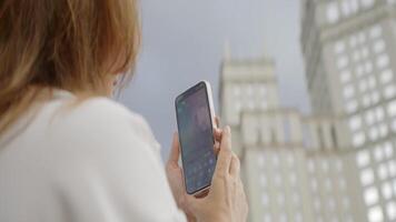 A Woman Utilizing Her Smartphone While Facing an Urban Skyline in a Beautiful City Setting. Action video