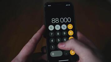 Close-up of man multiplying on phone. Media. Man is counting accounting bills on phone. Counting on calculator in phone video