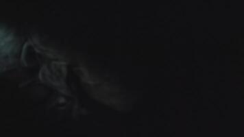 Close-up of smoke and ray of light in dark. Media. Streams of smoke move in dark with line of light. Light from spotlight illuminates beautiful streams of smoke in dark video