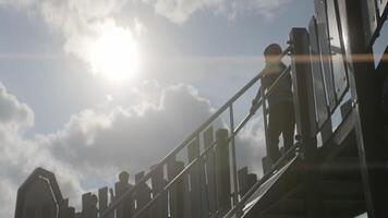 A happy child is joyfully playing on the colorful playground stairs under the bright sun. Action video