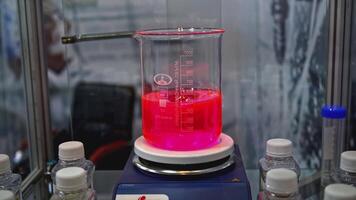 Rotating colored liquid in laboratory container. Media. Laboratory examination with colored liquid in large glass container. Rotating liquid in laboratory experiment video