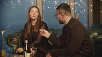 Friends chat and drink champagne in elegant restaurant. Media. Meeting friends with champagne in expensive restaurant. Elegant friends relax with champagne in restaurant in high-rise building video
