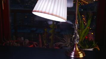 The lamp in the living room in front of window. Creative. Lamp on the table and evening city sky on the background. video