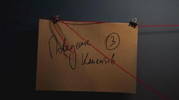 Note with inscription on wall. Stock footage. A note with an inscription on the wall. Close-up of note with inscription on red thread. Lantern lighting notes on string in night office video