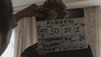 Man with clapperboard on set of movie. Stock. Man slaps clapperboard at beginning of movie shoot. Backstage with man and clapperboard before actors' actions video
