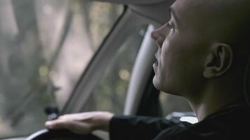 Rear view of driver driving car on summer day. Stock. View from passenger seat to driver of car. Cinematic car driving on sunny summer day video