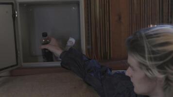 Man takes bottle out of drawer. Stock. Young man takes soda out of stash and drinks it. Young man drinks bottle of soda under stress video
