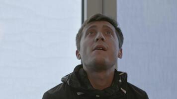 Close-up of man looking at room with reflections. Stock. Man with emotions looks at new room for work. Man entered room with panoramic windows and admired interior video