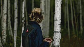 Man wanders in forest and looks around anxiously. Stock. Young man walks in woods with phone and looks around anxiously. Man is lost in woods with phone and looks around in fear video