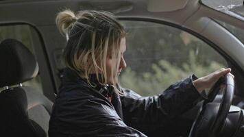 Young man worries and looks at phone in car. Stock. Man looks at phone during nervous breakdown in car. Man is nervous sitting in car and looking at phone video