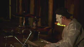 Man in mask plays rock drums. Clip. Masked drummer is actively playing on background of fire in forest. Masked man plays drums at festival in night forest video