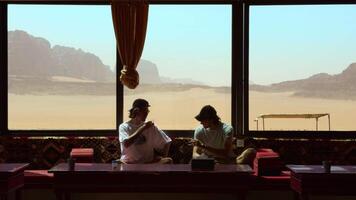 Two Adventurous Travelers Relishing the Stunning Desert View from Their Cozy Retreat Spot. Action video