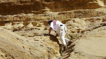 A determined climber skillfully ascending the challenging rocky terrain in a vast desert landscape. Action video