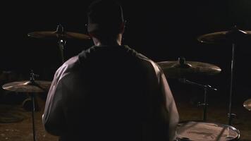Man sitting at drum set. Clip. Rear view of man sitting at drums. Man with bananas is preparing to join at night video