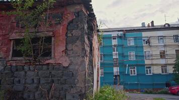 Abandoned houses on background of residential buildings. Clip. Abandoned buildings in village on background of residential high-rise buildings. Contrast of poor neighborhood with abandoned and video