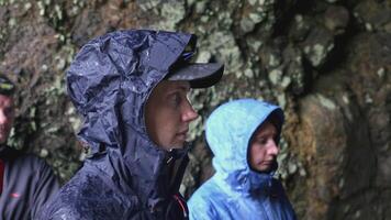 Tourist group trip to cave. Clip. Group of tourists stands at entrance to cave and listens anxiously to briefing. Group hike with instructor to caves video