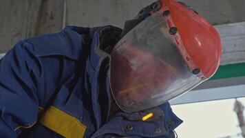 Masked man with sawing jobs at construction site. Clip. Worker in uniform and mask for working with circular saw. Masked worker cuts metal pipes with circular saw video