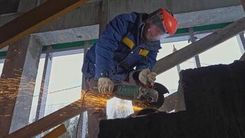 Masked man with sawing jobs at construction site. Clip. Worker in uniform and mask for working with circular saw. Masked worker cuts metal pipes with circular saw video