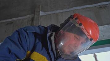 Masked man with sawing jobs at construction site. Clip. Worker in uniform and mask for working with circular saw. Masked worker cuts metal pipes with circular saw video
