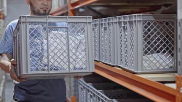 Man worker putting plastic box on the shelf at the factory warehouse. Media. Industrial background with goods on shelves. video
