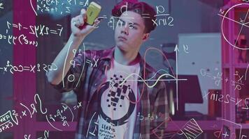 Man solves equations on transparent board. Media. Young man solves equations in closed laboratory. Man solves mathematical equations on blackboard with marker video