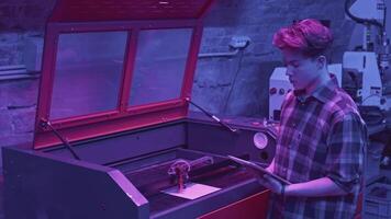 Man watches printing process. Media. Young developer monitors printer operation from tablet. Modern development of robotic printer in laboratory video