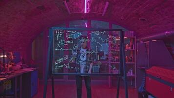 Young man solves equations in laboratory. Media. Student solves mathematical equations in secret classroom. Laboratory for experiments with mathematical calculations on blackboard video