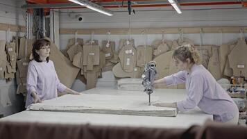 Details of a workshop of textile fabric. Media. Women cutting many layers of fabric with a special electrical saw. video
