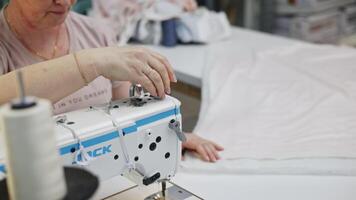 Close up of white sewing threads are unwound from spools on a sewing machine. Media. Production sewing in a textile factory. video