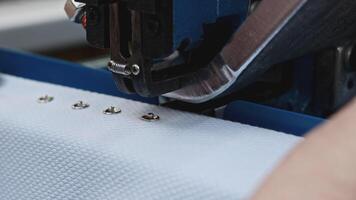 Automatic punching press machine at sewing factory. Media. Installing buttons on cloth with snap button machine. video