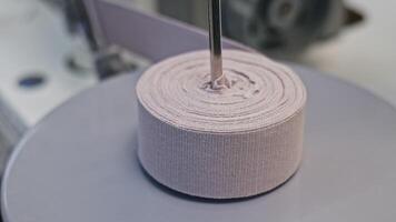 Close up of roll of pink elastic band in production factory workshop. Media. Industrial background at the sewing workshop. video