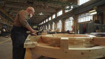 A skilled craftsman is diligently working on a large wooden structure inside his workshop. Stock Clip video