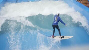 A Surfer Skillfully Riding a Wave in an Exciting Flow Rider Indoor Surfing Experience. Action video