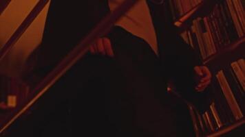 Man with a flashlight at night looking for documents in library. Stock footage. Man using flashlight to find a book on bookshelves. video