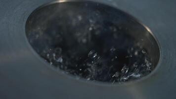 Close-up of bubbling water of metal container. Stock footage. Boiling water in metal container with hole. Special container for boiling water video