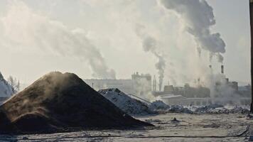 Quarry area with factories on background in winter. Stock footage. Fantastic view of land from quarry and factories with smoke in winter. Industrial area with smoke from factory chimneys on winter day video