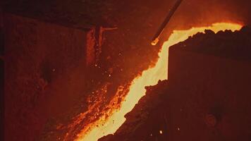 Streams and channels of molten metal. Stock footage. Worker crushes place for molten metal to flow with metal shelf. Solidified metals in path of molten alloy video