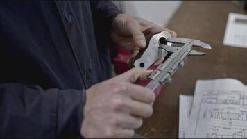 Worker measures part from drawings. Stock clip. Specialist makes measurements of metal part for project. Measurements and drawings of steel part at factory video