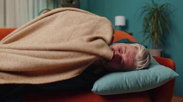 Tired middle-aged mature man lying down in bed taking a rest at home, napping falling asleep on sofa video