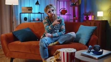 Man sitting on couch eating popcorn and watching interesting TV serial, sport game online at home video