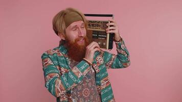 Hippie redhead man using retro vintage tape record player to listen music, disco dancing having fun video