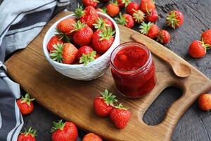 Homemade strawberry jam or marmalade in the glass jar and the fresh strawberries on the wooden rustic table photo