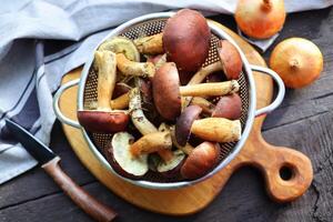 Forest boletus mushrooms on rustic wooden background and a wooden cutting board photo
