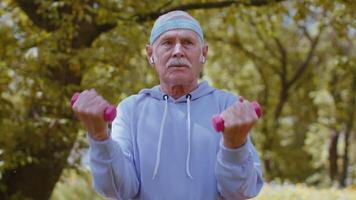Senior man exercising, making dumbbell weight lifting exercises, practicing sports training in park video