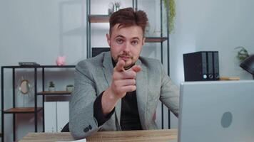 Businessman working on office laptop pointing to camera looking with happy expression making choice video