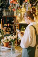 A woman in her florist shop collects bouquets of flowers. The concept of a small business. Bouquets of tulips for the holiday on March 8. photo