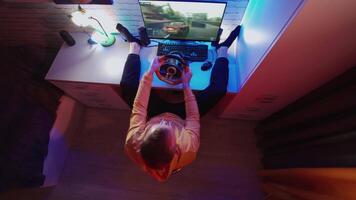 Male gamer playing racing game. Top view of young man concentrated on car racing game while sitting at home video